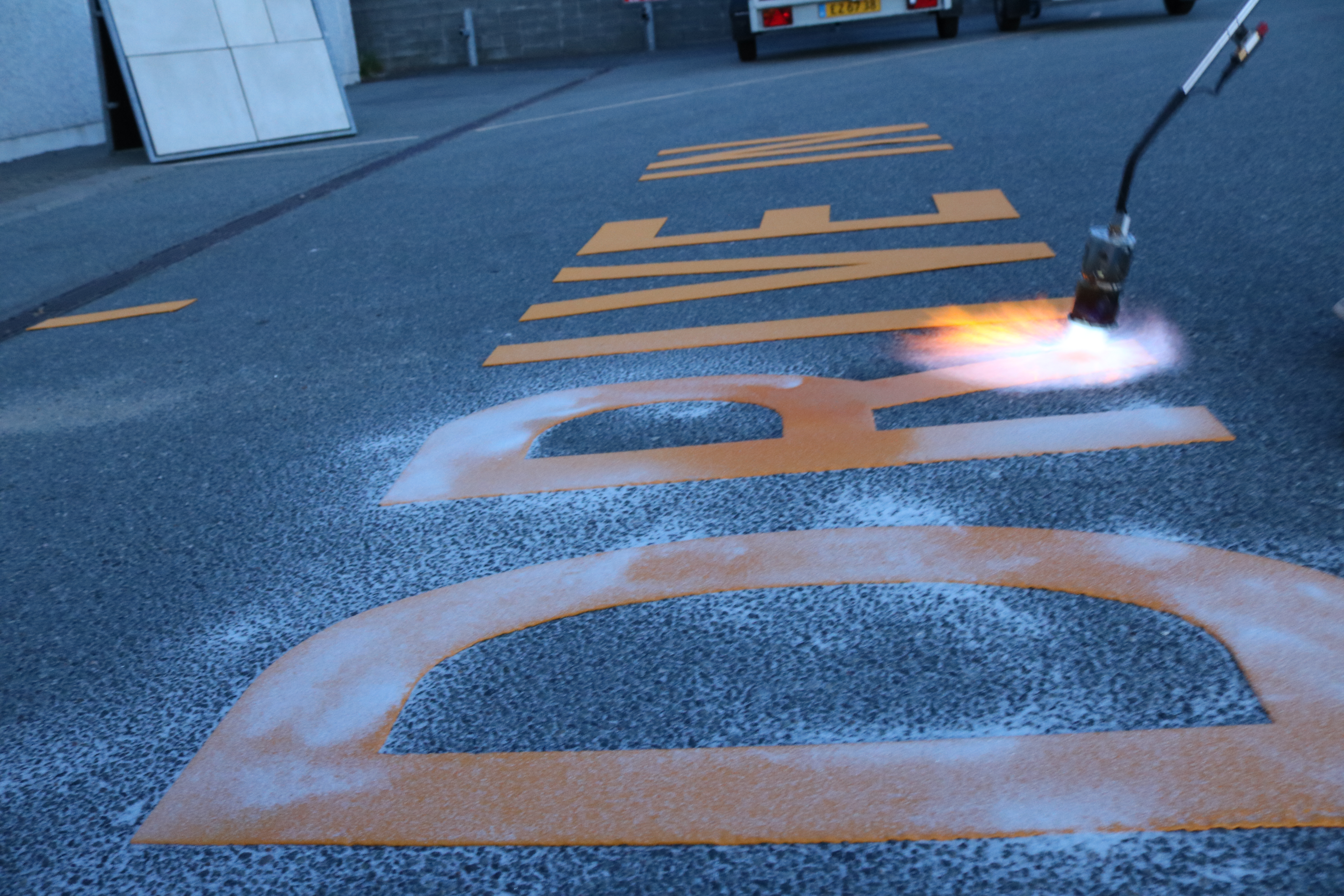Tekst "DRIVE IN" brændt på asfalt